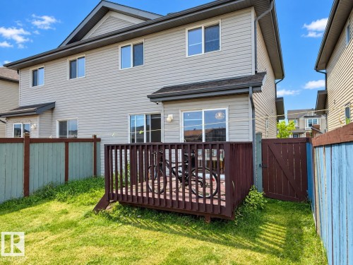 Exterior featuring light-colored siding, a dark-stained wood deck, and a fenced yard with a gate - 2829 18A Avenue Nw, Edmonton, AB 