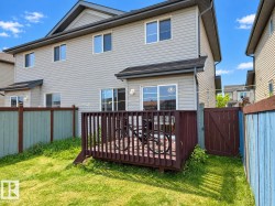 Exterior featuring light-colored siding, a dark-stained wood deck, and a fenced yard with a gate - 