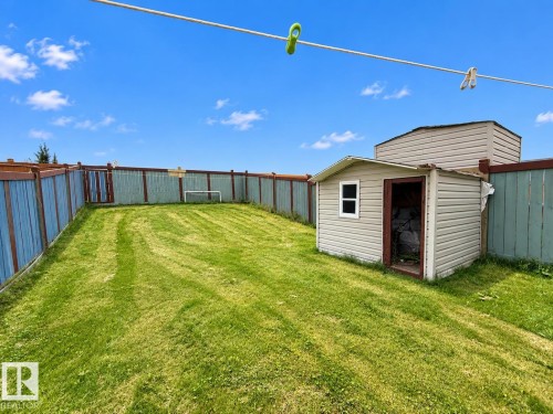 Expansive fenced yard featuring a storage shed with a window and a gate - 2829 18A Avenue Nw, Edmonton, AB 