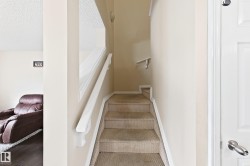 Carpeted staircase with white handrails and neutral painted walls - 