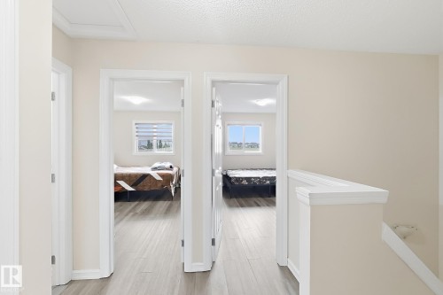 Hallway with wood-finish flooring, light neutral wall paint, and white trim - 2829 18A Avenue Nw, Edmonton, AB 