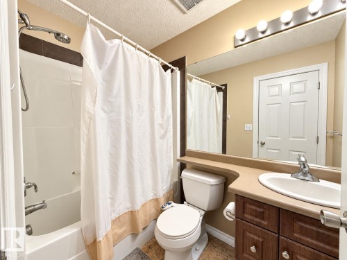 Built-in vanity with a single basin sink, wood-finish cabinetry, and an expansive mirror - 2829 18A Avenue Nw, Edmonton, AB 