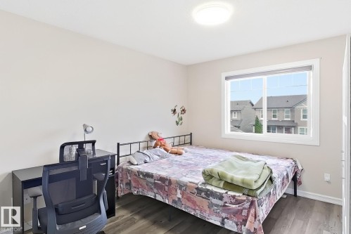 Light-filled room featuring a large window, neutral wall tones, wood-finish flooring, and a flush-mount ceiling light - 2829 18A Avenue Nw, Edmonton, AB 