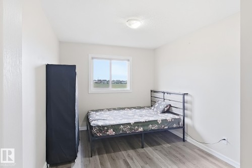 Light-colored walls with wood-finish flooring, featuring a window with a white frame and a ceiling-mounted light fixture - 2829 18A Avenue Nw, Edmonton, AB 