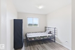 Light-colored walls with wood-finish flooring, featuring a window with a white frame and a ceiling-mounted light fixture - 