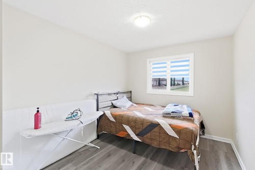 Wood-finish flooring with white baseboards, a single window with blinds, and an overhead flush-mount light fixture - 2829 18A Avenue Nw, Edmonton, AB 