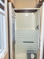 Shower enclosure with frosted glass door, chrome hardware, and tiled surround - 