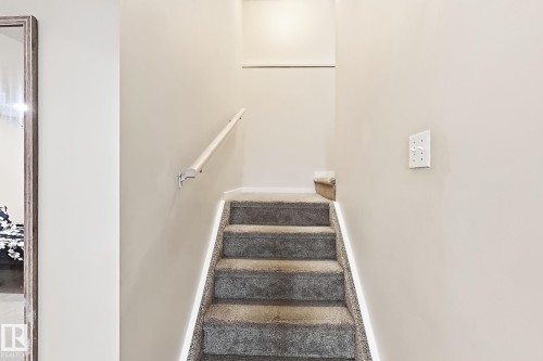 Carpeted staircase with an attached handrail and light-colored wall paint - 2829 18A Avenue Nw, Edmonton, AB 