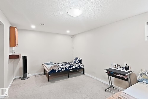 Recessed lighting and a flush-mount ceiling fixture illuminate this carpeted room - 2829 18A Avenue Nw, Edmonton, AB 