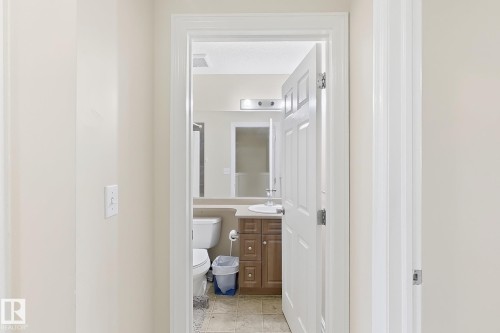 Bathroom featuring a vanity with wood-finish cabinetry, a single basin sink, and a wall-mounted mirror - 2829 18A Avenue Nw, Edmonton, AB 