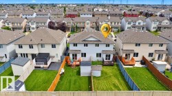 Expansive fenced backyard with a manicured lawn, a multi-level deck, two storage sheds, and a covered patio area - 