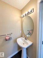 Pedestal sink with chrome fixtures, oval mirror, and a four-bulb vanity light - 