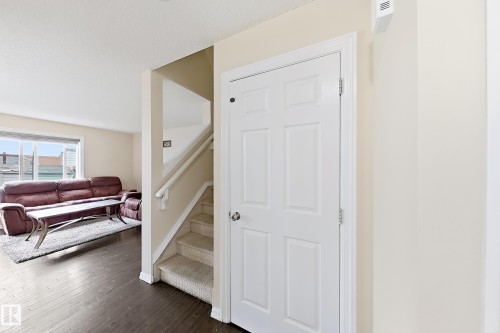 Rich wood-finish flooring, staircase with carpeting, white paneled interior door, and light-toned wall finishes - 2829 18A Avenue Nw, Edmonton, AB 