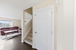 Rich wood-finish flooring, staircase with carpeting, white paneled interior door, and light-toned wall finishes - 