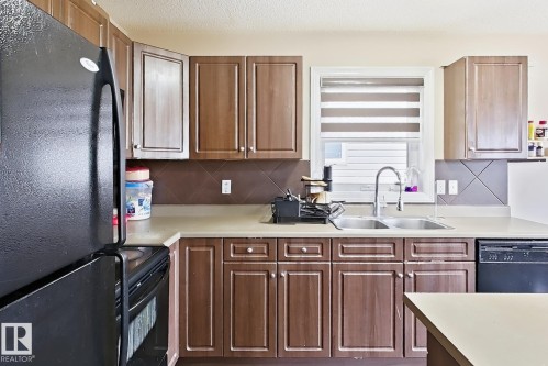 Kitchen featuring wood-finish cabinetry, light countertops, and a dual basin sink with a high-arc faucet - 2829 18A Avenue Nw, Edmonton, AB 