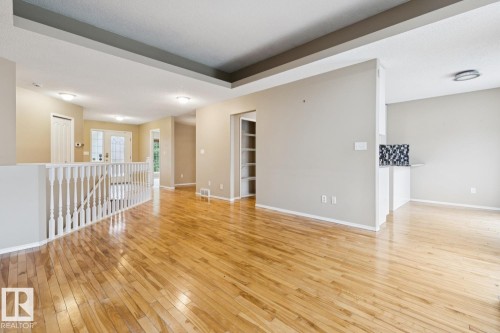 Expansive wood-finish flooring, recessed lighting, white baluster railing, built-in shelving, and a decorative tile backsplash - 1190 Potter Greens Drive Nw, Edmonton, AB 
