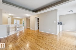 Expansive wood-finish flooring, recessed lighting, white baluster railing, built-in shelving, and a decorative tile backsplash - 