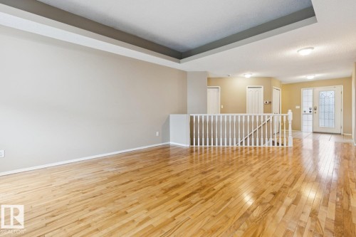 Tray ceiling detail, wood-finish flooring, white railing, and decorative glass entry doors - 1190 Potter Greens Drive Nw, Edmonton, AB 