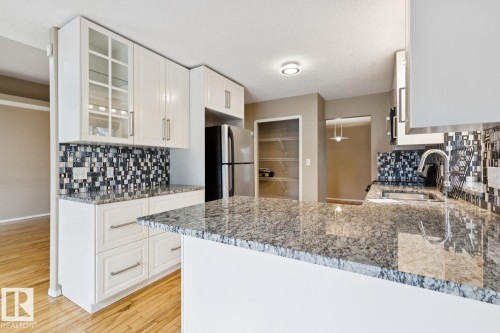 White cabinetry with glass-front uppers, stainless steel appliances, granite countertops, and a mosaic tile backsplash - 1190 Potter Greens Drive Nw, Edmonton, AB 