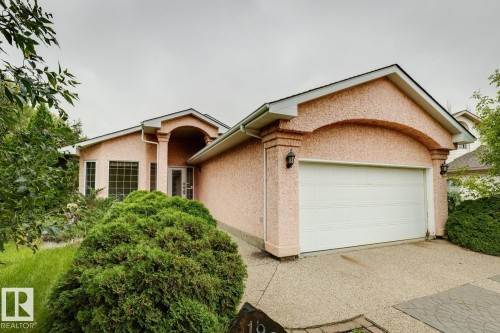 Stucco exterior with a peaked roofline, arched entryway, and an attached two-car garage - 1190 Potter Greens Drive Nw, Edmonton, AB 