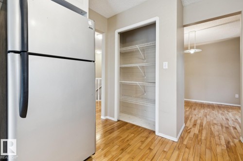 Stainless steel refrigerator, wire shelving, wood-finish flooring, recessed lighting, and a contemporary pendant fixture - 1190 Potter Greens Drive Nw, Edmonton, AB 