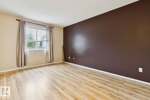 Wood-finish flooring with base molding, a white-framed window, and a textured ceiling - 1190 Potter Greens Drive Nw, Edmonton, AB 