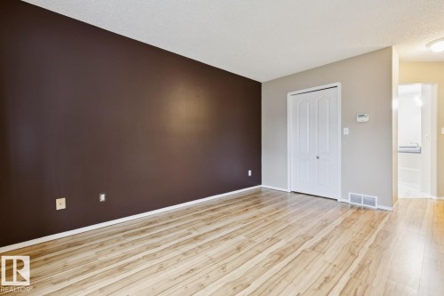 Wood-finish flooring throughout, with a contrasting accent wall, bi-fold closet doors, and recessed lighting - 1190 Potter Greens Drive Nw, Edmonton, AB 