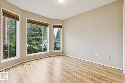 Bay window with multiple large glass panels, wood-finish flooring, neutral wall tones, and white trim - 1190 Potter Greens Drive Nw, Edmonton, AB 