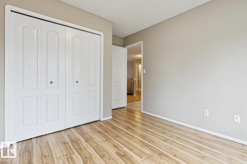 Wood-finish flooring, white bi-fold closet doors, and neutral wall tones - 1190 Potter Greens Drive Nw, Edmonton, AB 