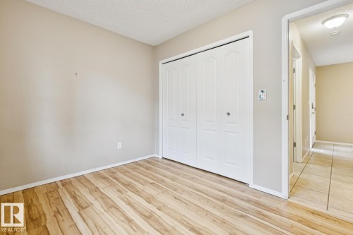 Wood-finish flooring, neutral wall paint, and bi-fold closet doors - 1190 Potter Greens Drive Nw, Edmonton, AB 