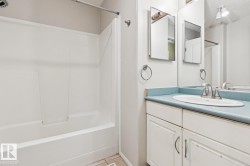 White bathtub and shower combination with a single-basin vanity featuring an oval sink and a light blue countertop - 
