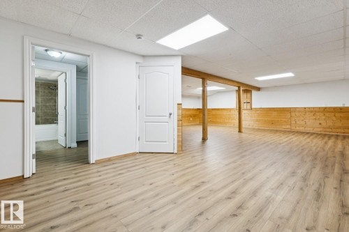 Spacious room with wood-finish flooring, white walls, and wood paneling - 1190 Potter Greens Drive Nw, Edmonton, AB 