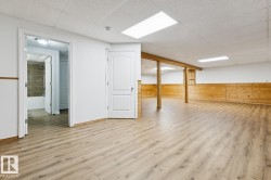 Spacious room with wood-finish flooring, white walls, and wood paneling - 