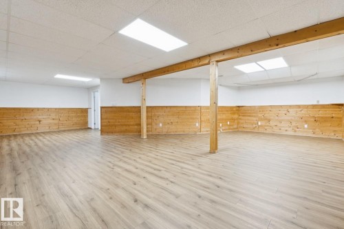 Spacious room featuring wood-finish flooring, wood-paneled wainscoting, and recessed ceiling lighting - 1190 Potter Greens Drive Nw, Edmonton, AB 