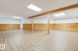 Spacious room featuring wood-finish flooring, wood-paneled wainscoting, and recessed ceiling lighting - 