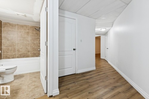 Bathroom with a white tub, shower with tan tile surround, and a toilet - 1190 Potter Greens Drive Nw, Edmonton, AB 