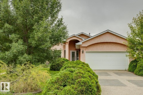 Stucco exterior with arched entryway and garage door framing - 1190 Potter Greens Drive Nw, Edmonton, AB 