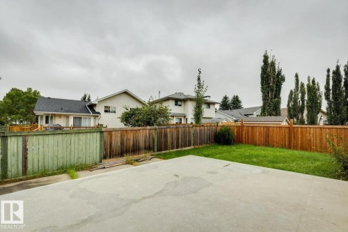 Expansive concrete patio with a manicured lawn and mature privacy fencing - 1190 Potter Greens Drive Nw, Edmonton, AB 