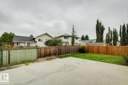 Expansive concrete patio with a manicured lawn and mature privacy fencing - 