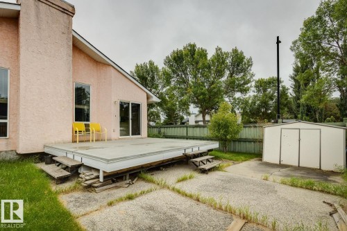 Exterior featuring stucco siding, multiple windows, a rear deck with steps, a sliding glass door, and a detached storage shed - 1190 Potter Greens Drive Nw, Edmonton, AB 