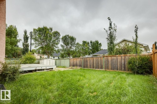 Expansive backyard space featuring a wooden privacy fence, a raised deck platform, a storage shed, and mature perimeter trees - 1190 Potter Greens Drive Nw, Edmonton, AB 