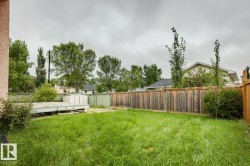 Expansive backyard space featuring a wooden privacy fence, a raised deck platform, a storage shed, and mature perimeter trees - 