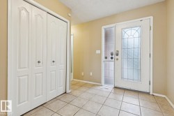Entryway featuring tile flooring, a decorative glass entry door, an opaque glass sidelight, and bi-fold closet doors - 