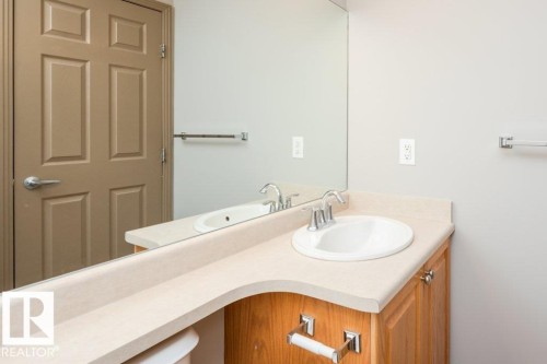 Wood-finish vanity with a built-in sink and chrome faucet - 401 5005 165 Avenue Nw, Edmonton, AB 