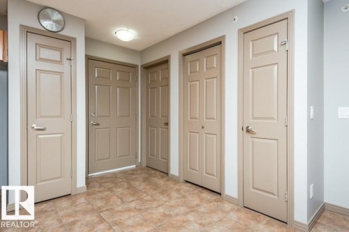 Entryway featuring tile flooring, neutral wall tones, and multiple panel doors - 401 5005 165 Avenue Nw, Edmonton, AB 