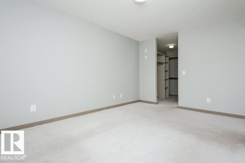 Carpeted flooring, light gray walls, built-in closet shelving, recessed lighting, and a neutral color palette - 401 5005 165 Avenue Nw, Edmonton, AB 