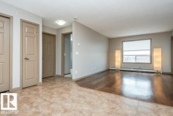 Expansive room featuring wood-finish flooring, a large window with roller shade, and neutral wall tones - 