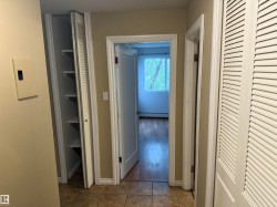 Tile flooring, louvered bi-fold closet doors, built-in shelving, wood-finish flooring, and white trim - 