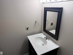 Vanity with a white countertop and integrated sink, chrome faucet, framed wall mirror, and overhead vanity lighting - 