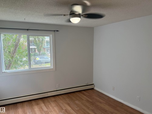 Wood-finish flooring, white trim, and light gray walls - #205 10335 117 St Nw, Edmonton, AB 